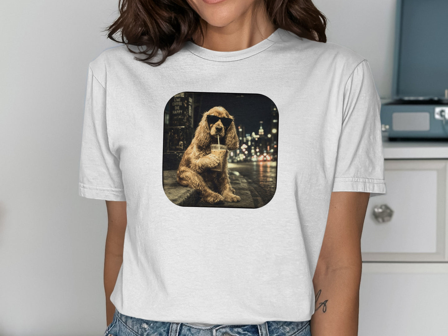 Cocker spaniel wearing sunglasses drinks from a cup on a city street at night.