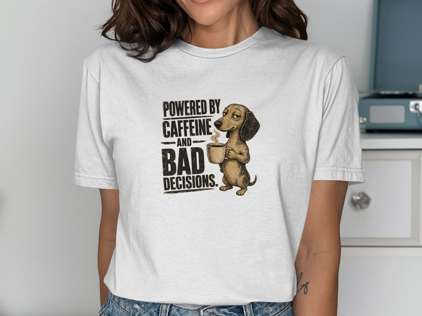 Dachshund wearing a shirt, holding a coffee mug, text "Powered by caffeine and bad decisions."