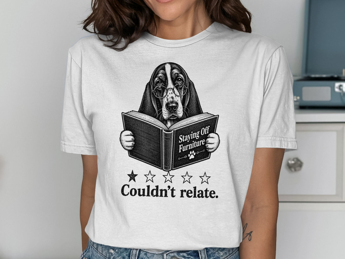 Woman wearing t-shirt with a basset hound reading a book titled "Staying Off Furniture".
