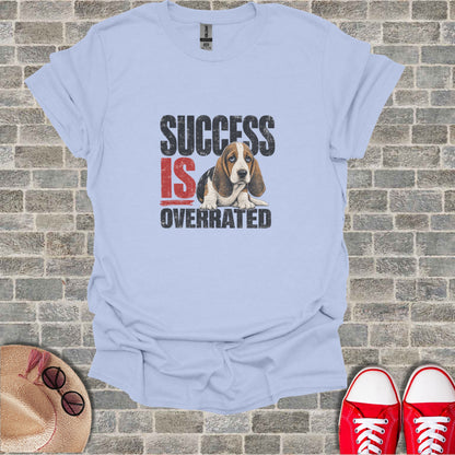 Light blue t-shirt with "SUCCESS IS OVERRATED" text and a sad basset hound.