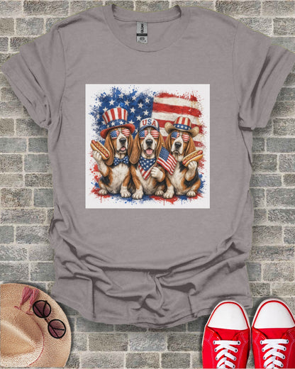 Three beagles wearing patriotic USA bandanas and sunglasses holding hot dogs.