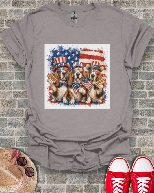 Three beagles wearing patriotic USA bandanas and sunglasses holding hot dogs.