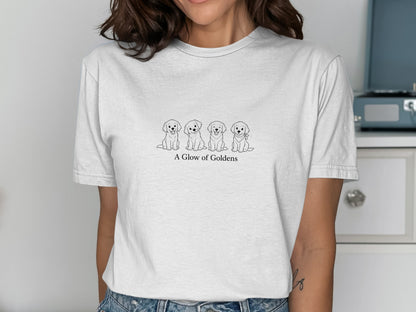 White t-shirt with a line drawing of four golden retriever puppies and the text "A Glow of Goldens".