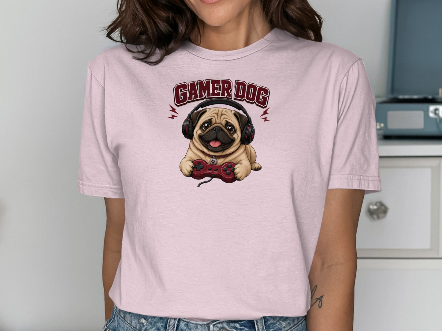 Pink t-shirt featuring a pug wearing headphones and holding a video game controller.