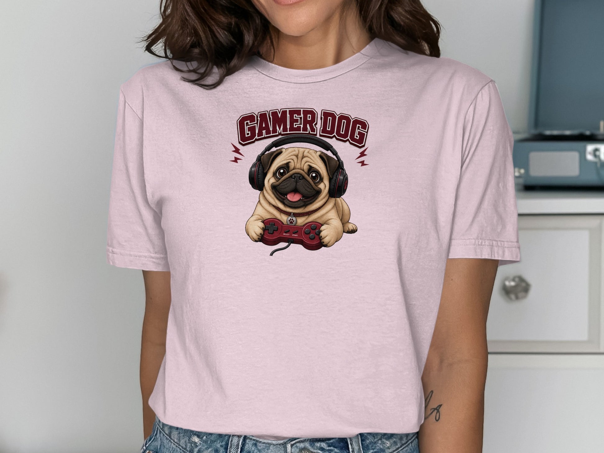 Pink t-shirt featuring a pug wearing headphones and holding a video game controller.