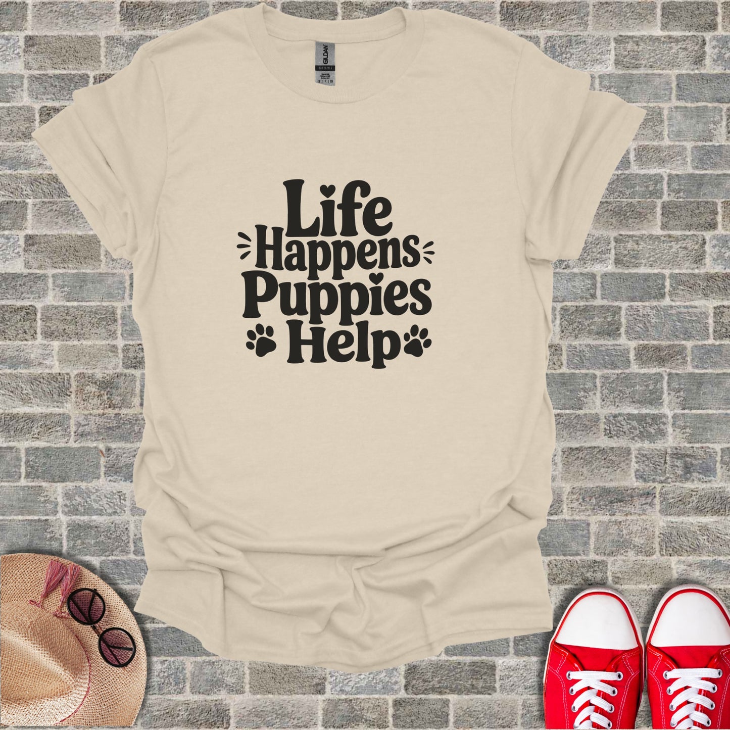 Cream t-shirt with black text "Life Happens Puppies Help" and paw prints.