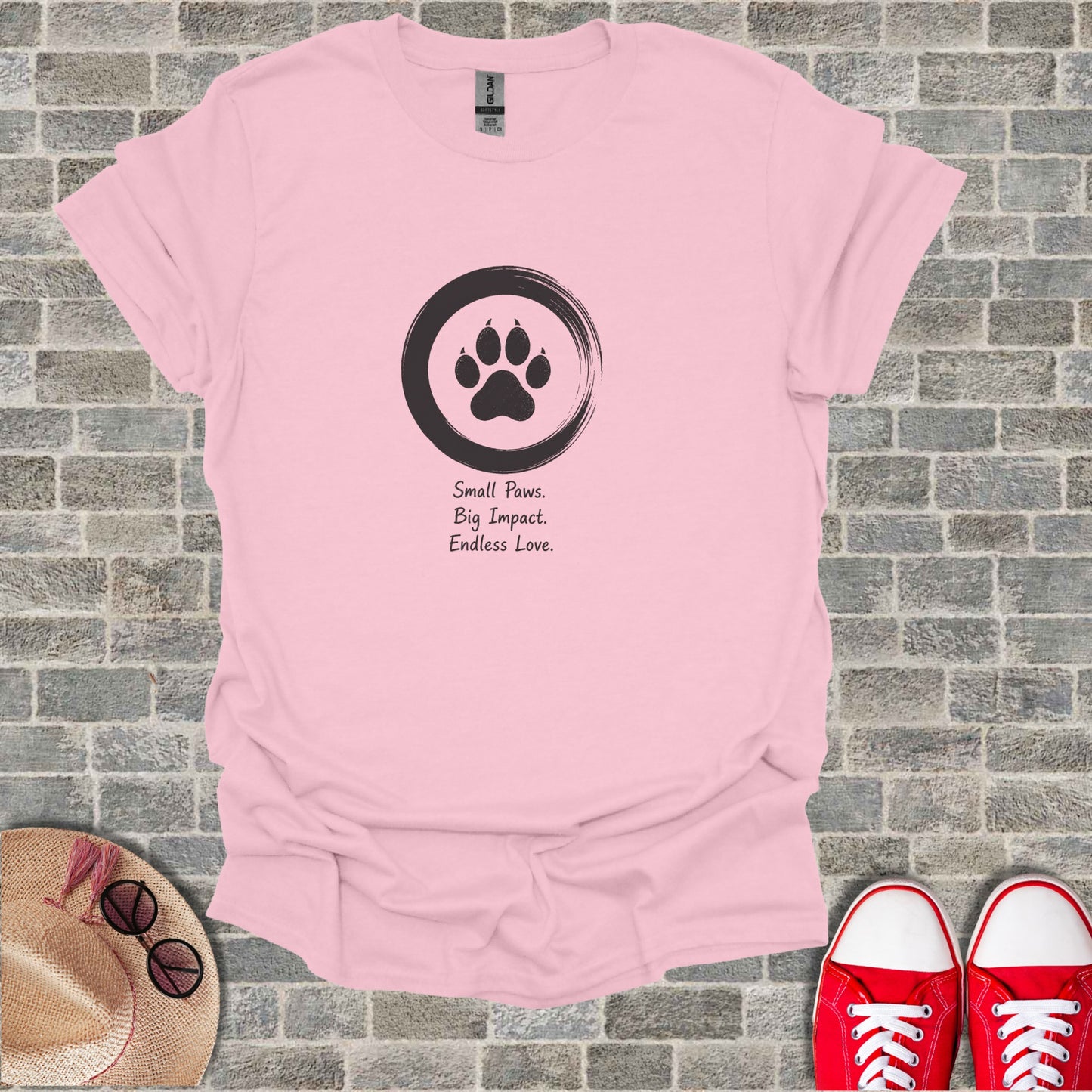 Pink t-shirt with black paw print logo and text "Small Paws. Big Impact. Endless Love."