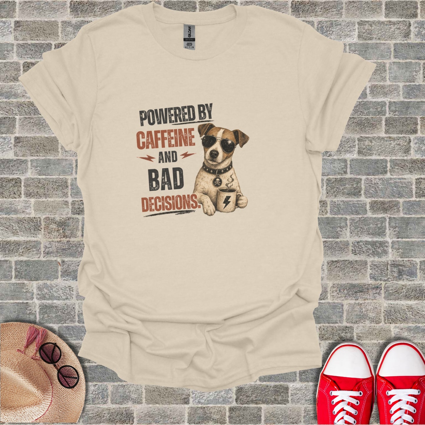 T-shirt graphic of a dog wearing sunglasses and a bandana, holding a coffee cup. Text reads: "POWERED BY CAFFEINE AND BAD DECISIONS".