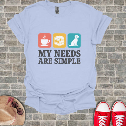 Light blue t-shirt with coffee, books, and dog icons and the text "MY NEEDS ARE SIMPLE".