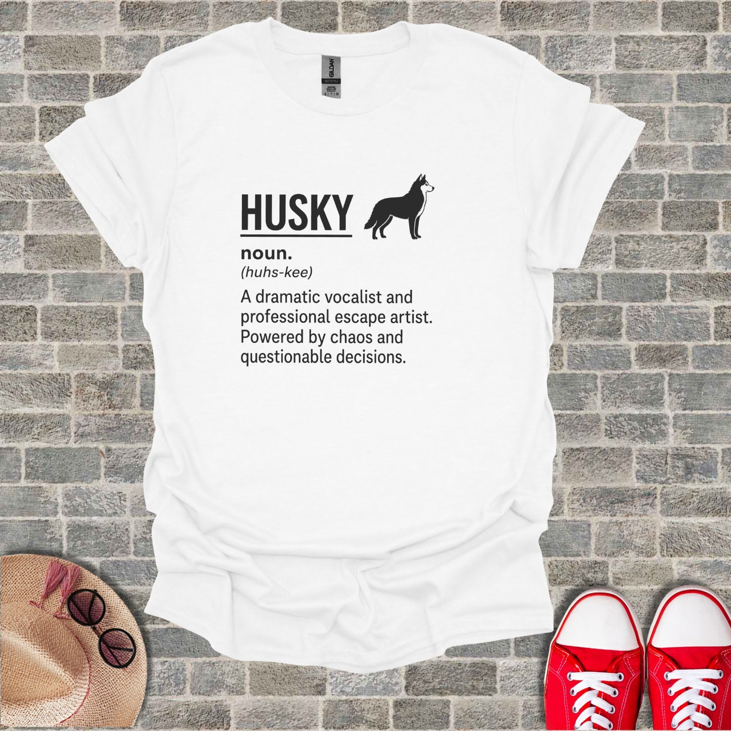 White t-shirt with black text and husky graphic: "HUSKY noun. (huhs-kee) A dramatic vocalist and professional escape artist. Powered by chaos and questionable decisions."