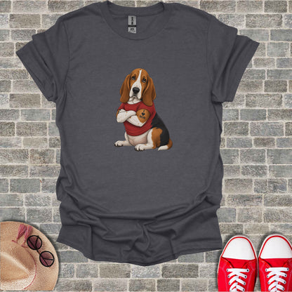Basset Hound wearing a t-shirt with "MOM" on it, sitting in front of a brick wall.