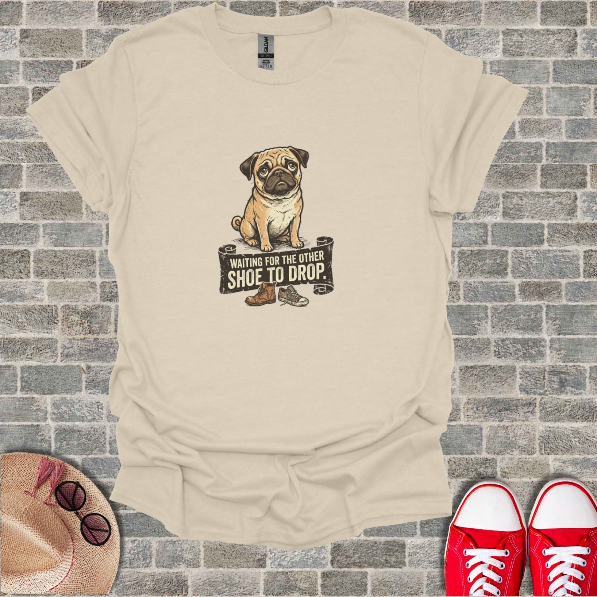 Pug waiting for the other shoe to drop, shown on a tan t-shirt.