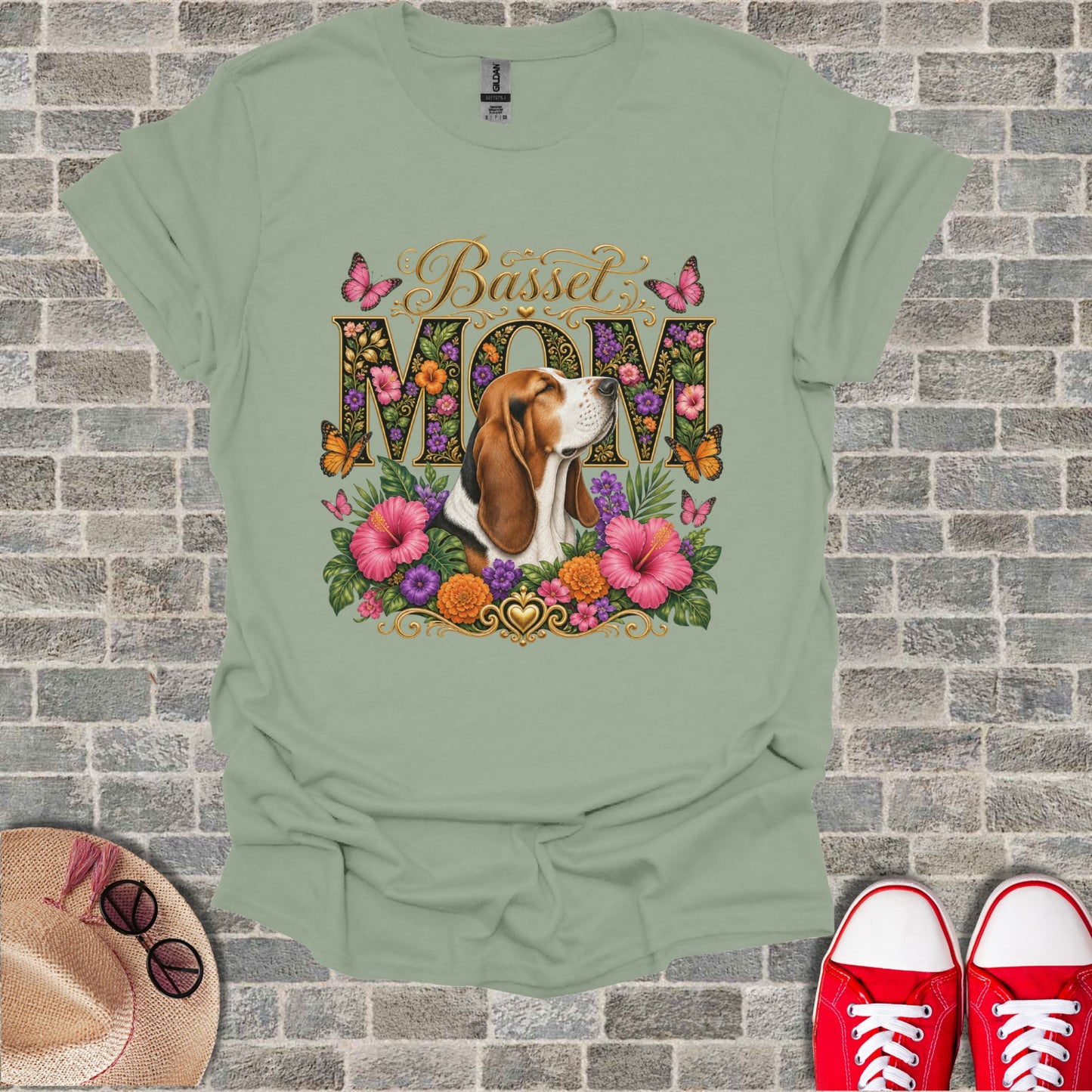 Basset Mom text with beagle, pink hibiscus, and butterflies graphic on a sage green t-shirt.