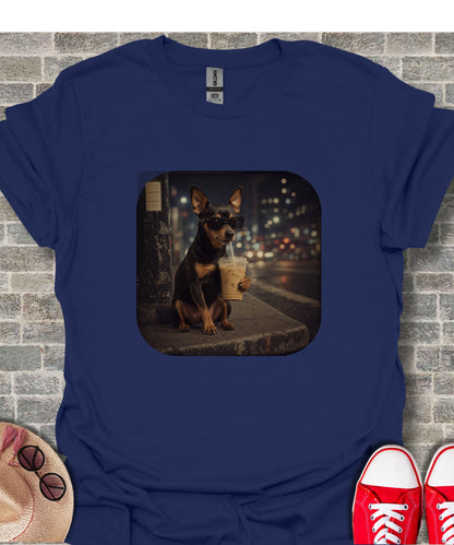 Dog wearing sunglasses drinks iced coffee with a city background on t-shirt.