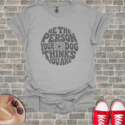 Light grey t-shirt with "Be the person your dog thinks you are" text graphic.
