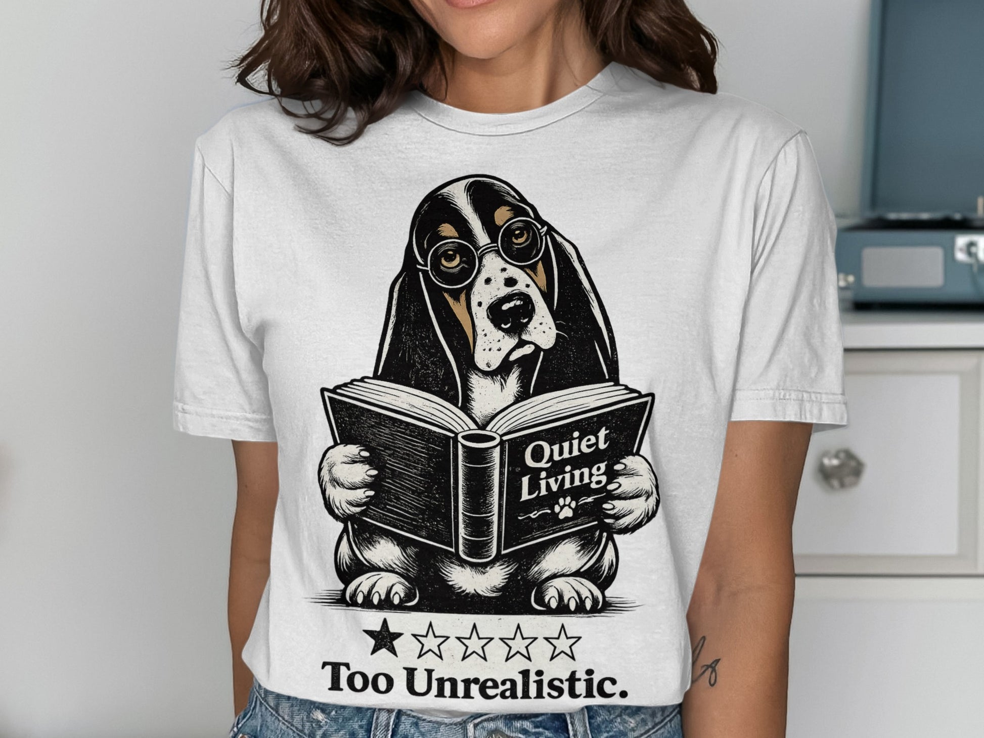 Basset hound wearing glasses reads a book titled "Quiet Living" on a t-shirt.