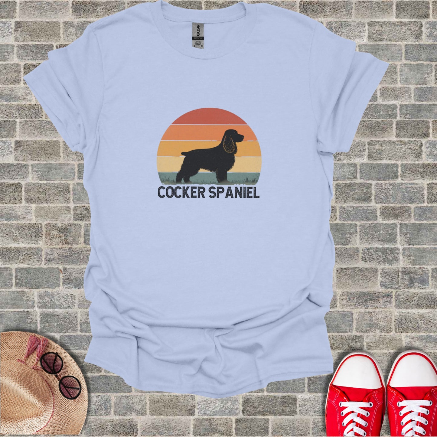 Light blue t-shirt with black cocker spaniel silhouette and sunset graphic.