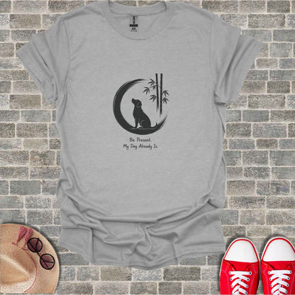 Gray t-shirt with a black graphic of a dog silhouette under bamboo and the text "Be Present. My Dog Already Is."