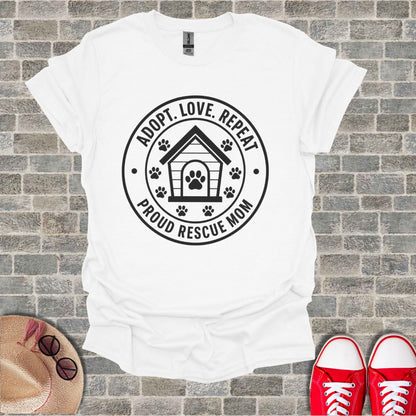 White t-shirt with "ADOPT. LOVE. REPEAT. PROUD RESCUE MOM" text and dog house graphic.