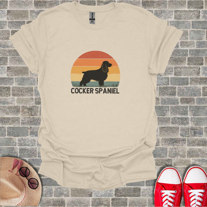 Beige t-shirt with a graphic of a cocker spaniel silhouette against a sunset.