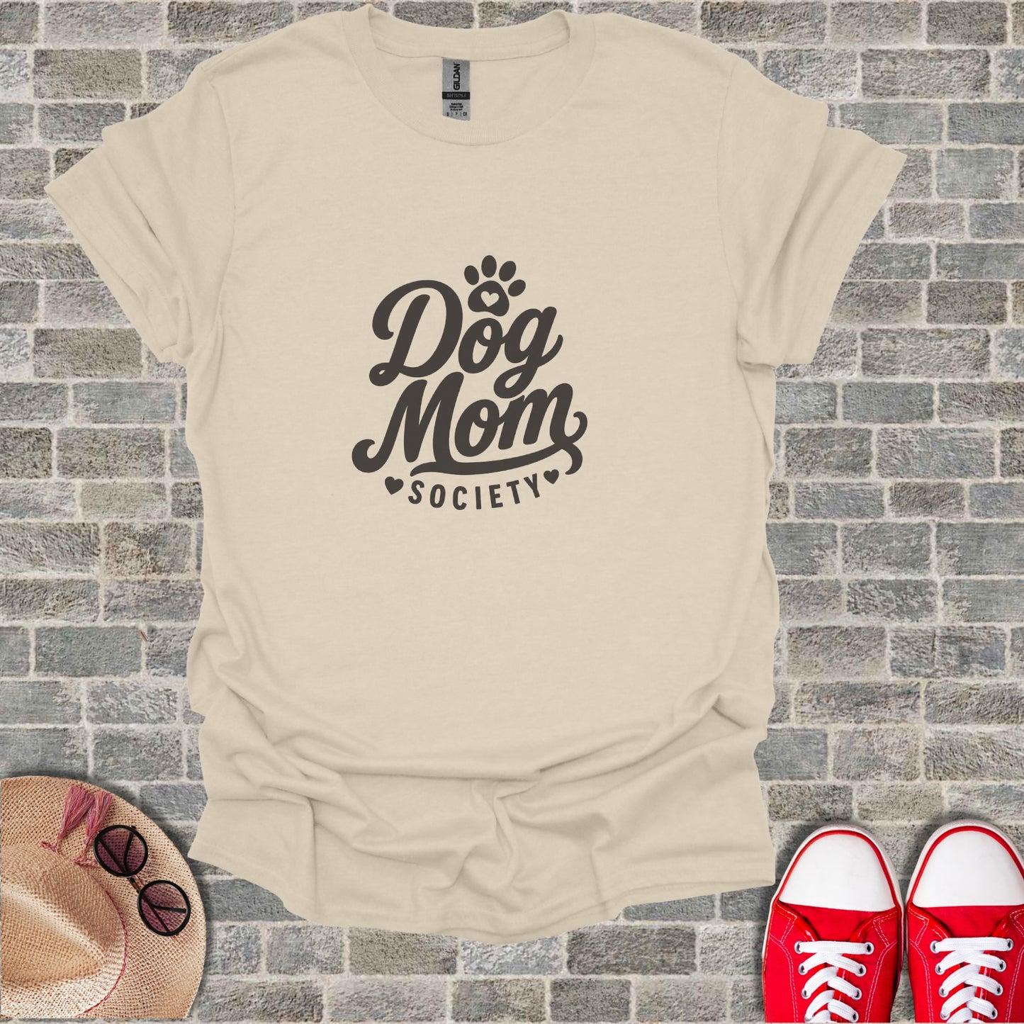 Cream t-shirt with "Dog Mom Society" graphic, straw hat, and red sneakers.