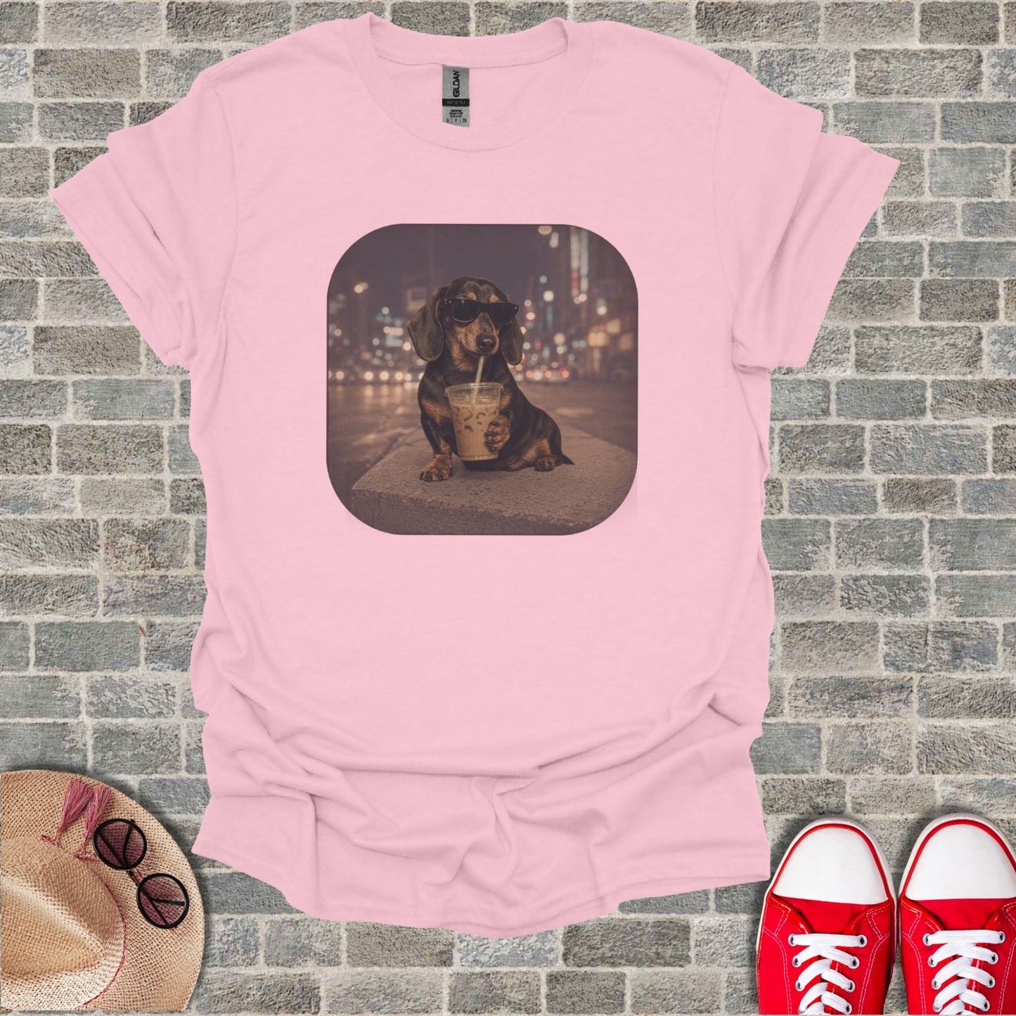 Dachshund in sunglasses drinks from a cup on a t-shirt graphic.