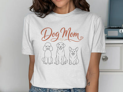 White t-shirt with "Dog Mom" text and line drawings of a poodle, labrador, and corgi.