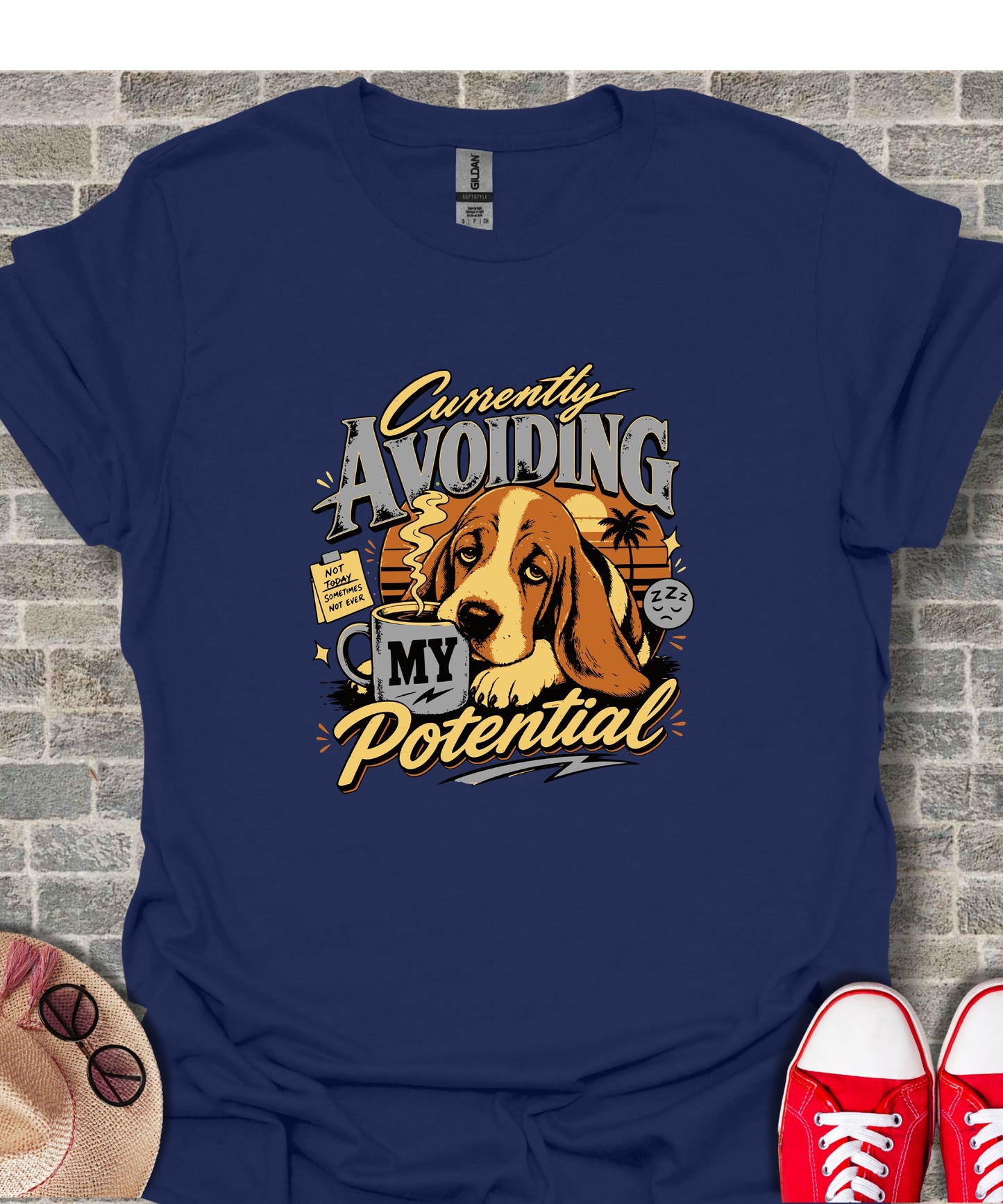Basset hound with coffee mug on navy shirt reading "Currently Avoiding My Potential."