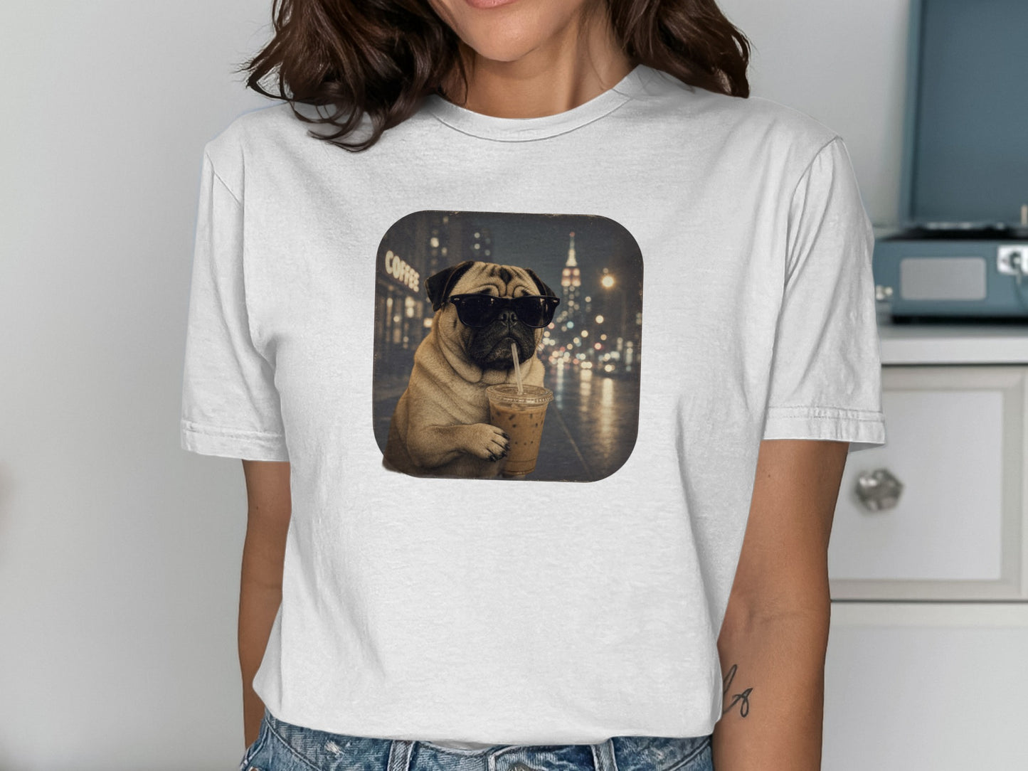 Pug wearing sunglasses holds iced coffee in front of a city night scene.