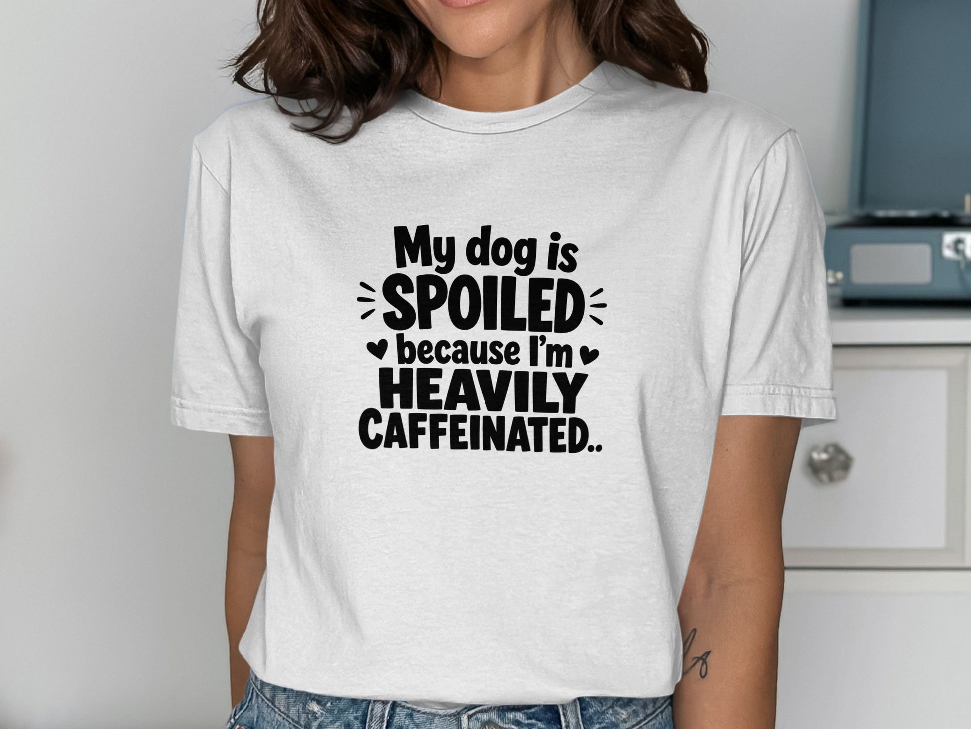 White t-shirt with black text: "My dog is spoiled because I'm heavily caffeinated."