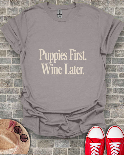 Gray t-shirt with "Puppies First. Wine Later." text, straw hat, and red sneakers.