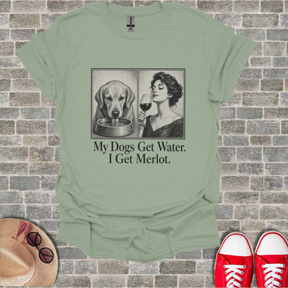 T-shirt with two illustrated panels: a dog drinking and a woman with wine. Text reads "My Dogs Get Water. I Get Merlot."