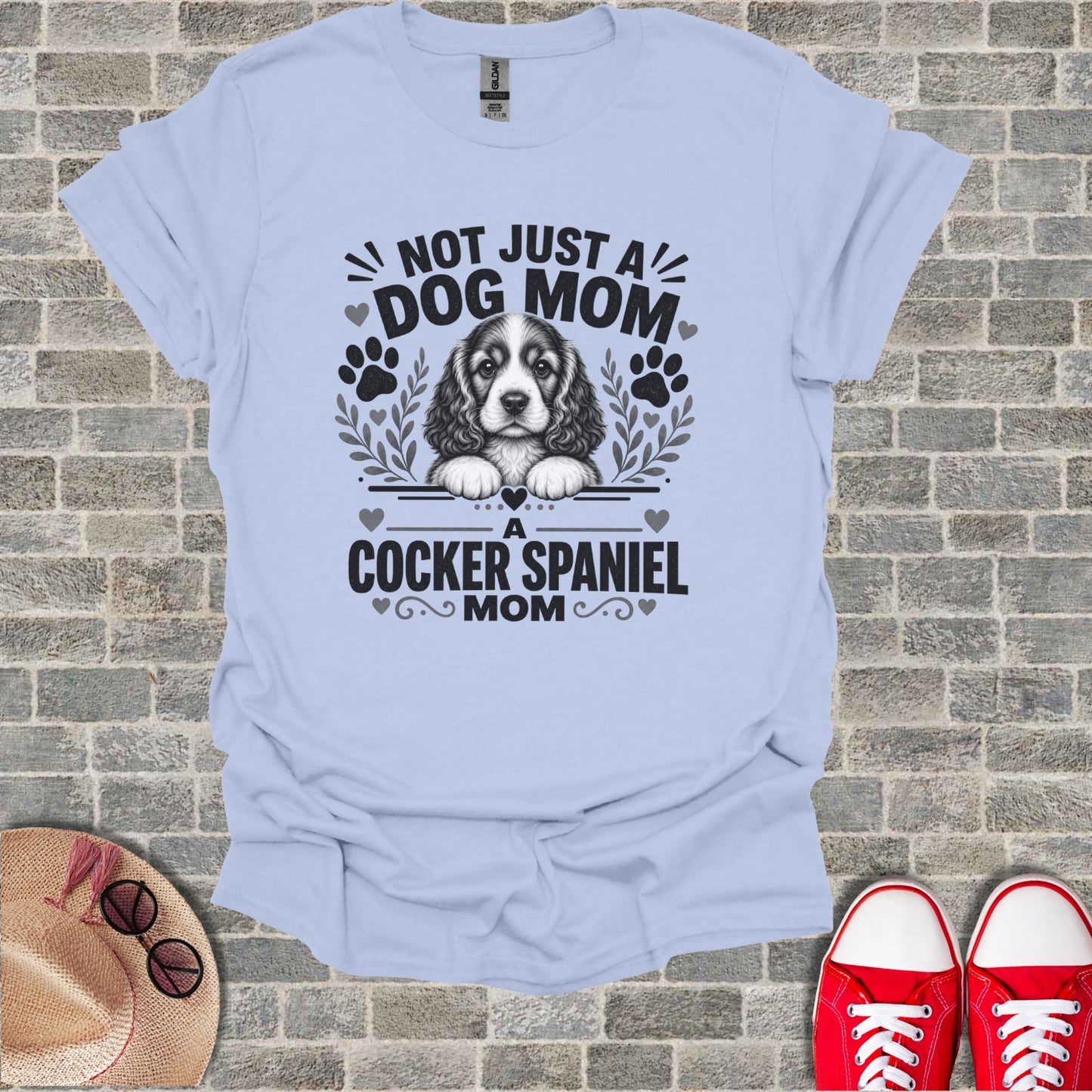 Light blue t-shirt with a Cocker Spaniel graphic and text "Not Just A Dog Mom, A Cocker Spaniel Mom".