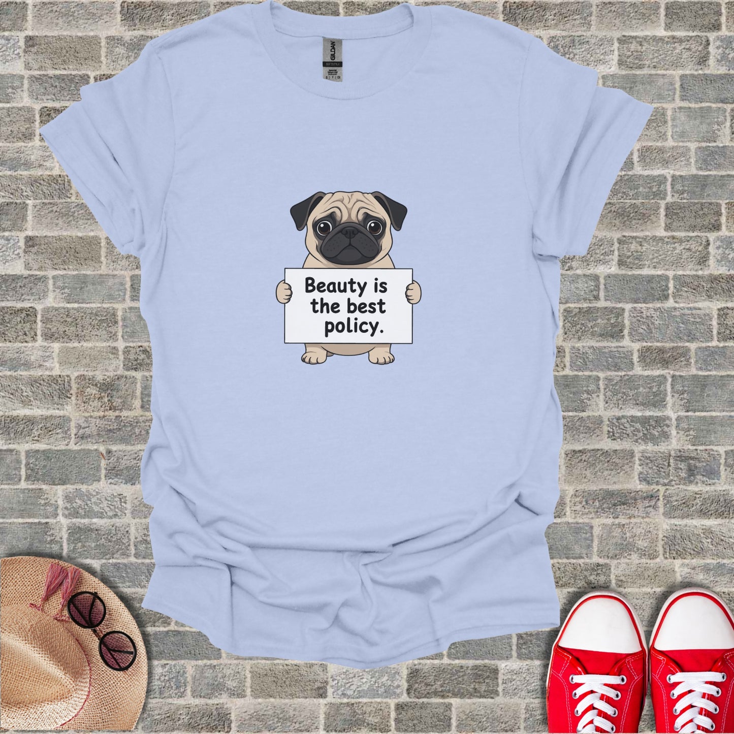 Light blue t-shirt with cartoon pug holding a sign that says "Beauty is the best policy."