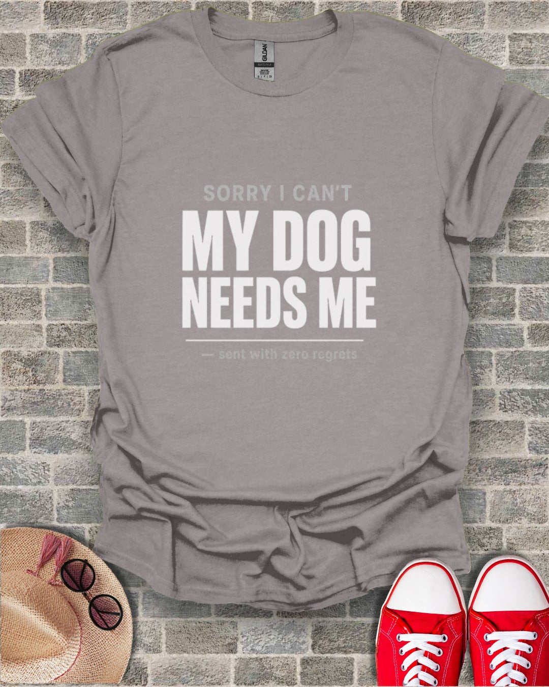 Gray t-shirt with white text reading "MY DOG NEEDS ME" and "sent with zero regrets".