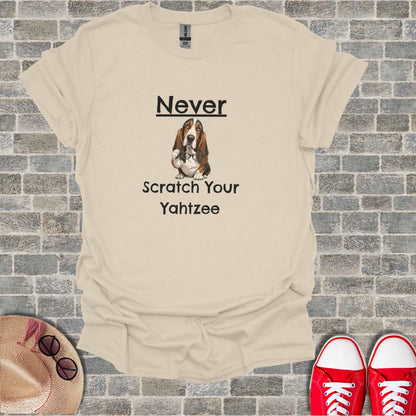 Cream t-shirt with a basset hound wearing glasses and the text "Never Scratch Your Yahtzee."
