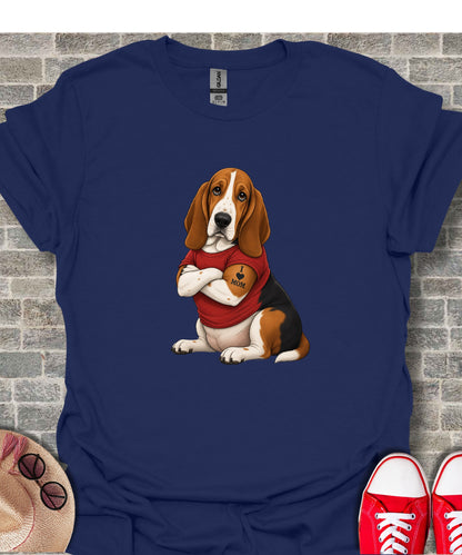 Basset hound with "I love Mom" tattoo on chest, wearing a t-shirt.
