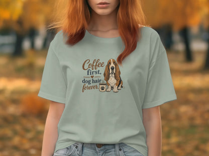 Basset hound wearing glasses with coffee cup, text "Coffee first, dog hair forever".