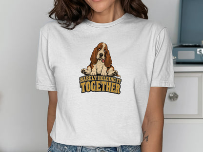 Basset Hound sitting with tongue out and text "barely holding it together".