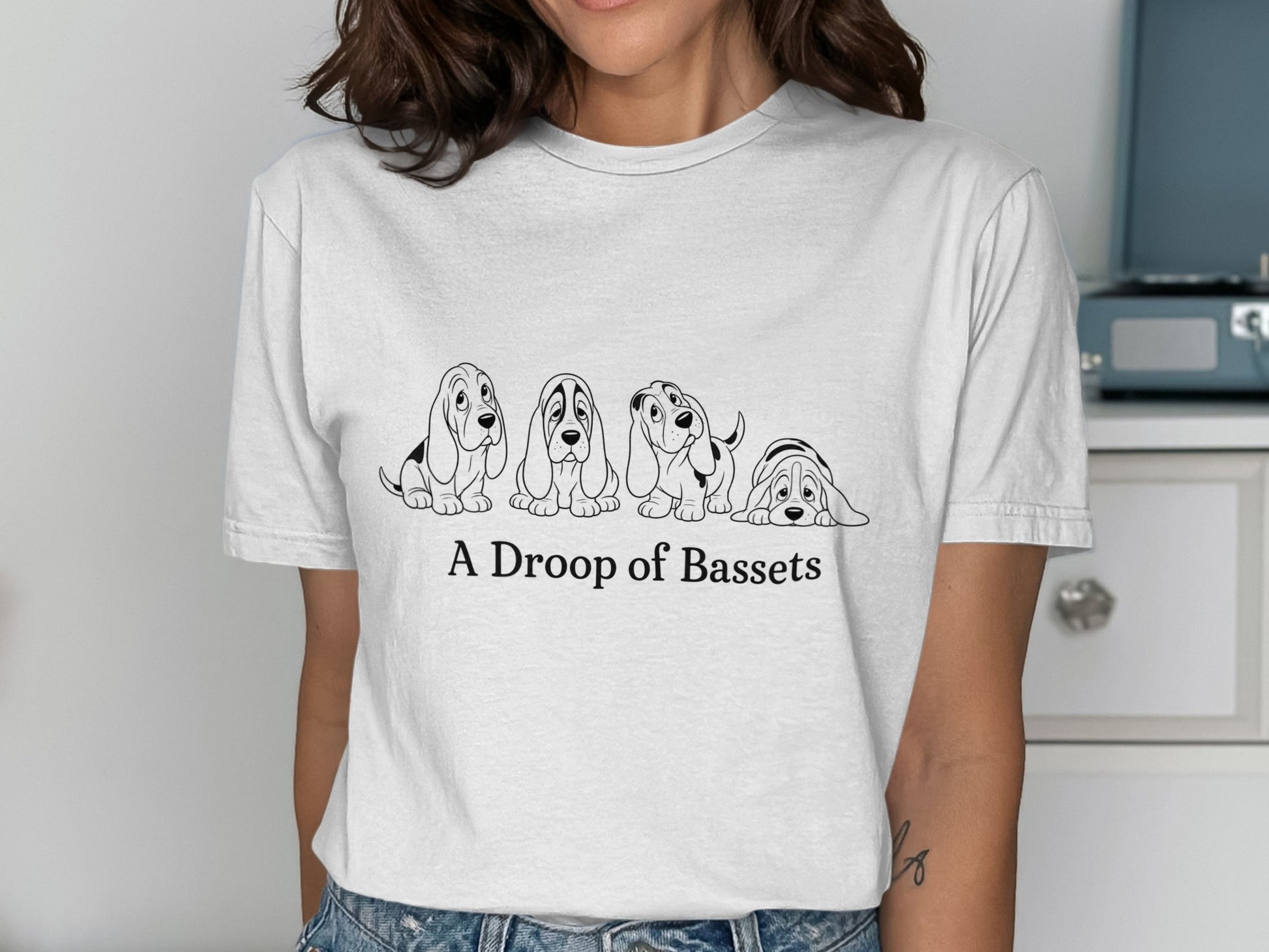 White t-shirt with "A Droop of Bassets" text and four cartoon Basset Hounds.