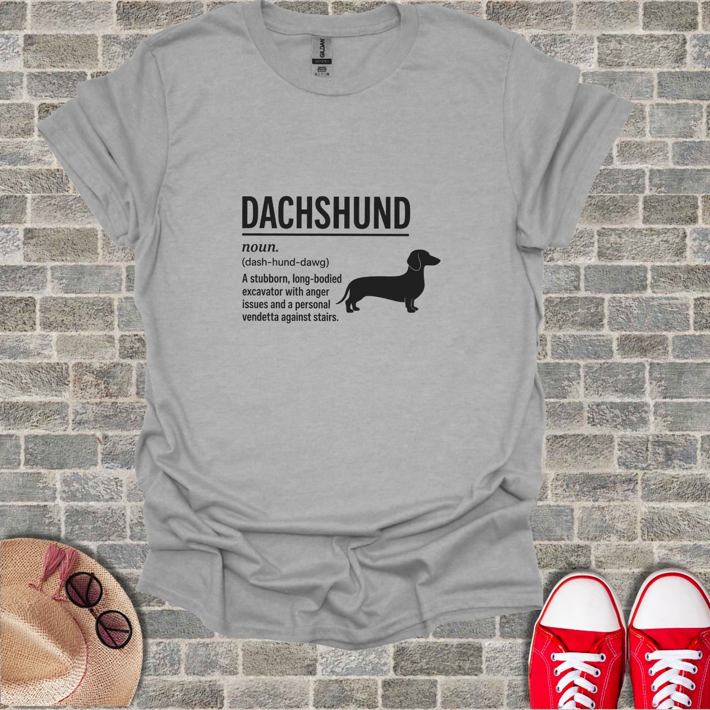 Gray t-shirt with "DACHSHUND noun. (dash-hund-dawg) A stubborn, long-bodied excavator with anger issues and a personal vendetta against stairs."