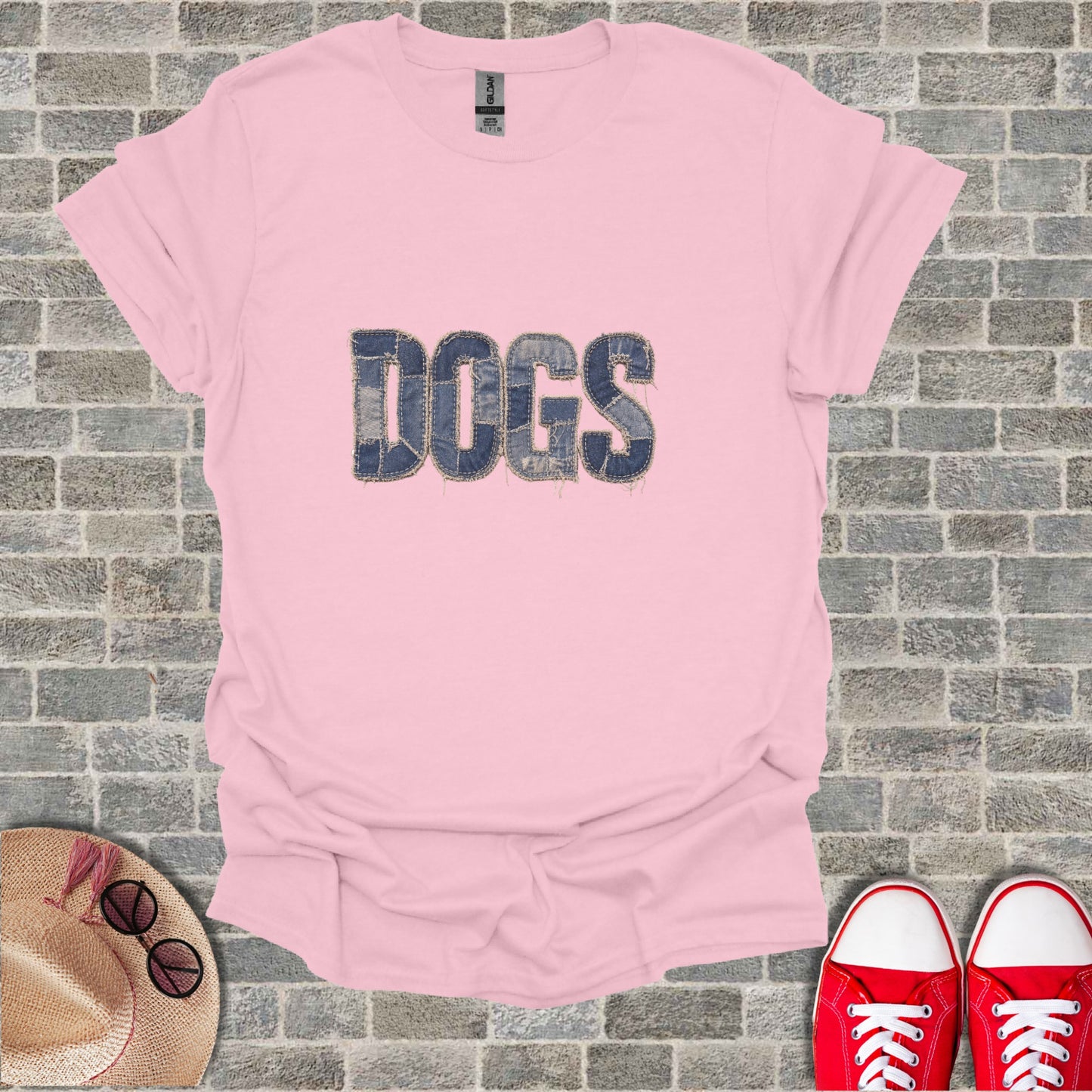 Pink t-shirt with "DOGS" in denim lettering, hat, and red shoes.