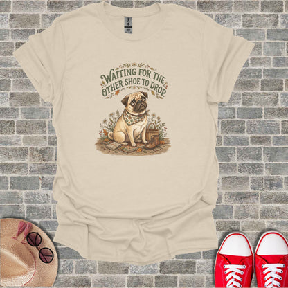 Pug wearing bandana sits near boot, text "Waiting for the other shoe to drop".