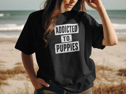 Black t-shirt with "ADDICTED TO PUPPIES" text on a beach background.