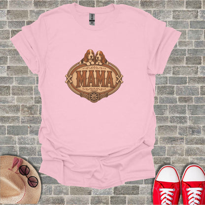 Pink t-shirt with "MAMA" and dog illustration, on a brick background.