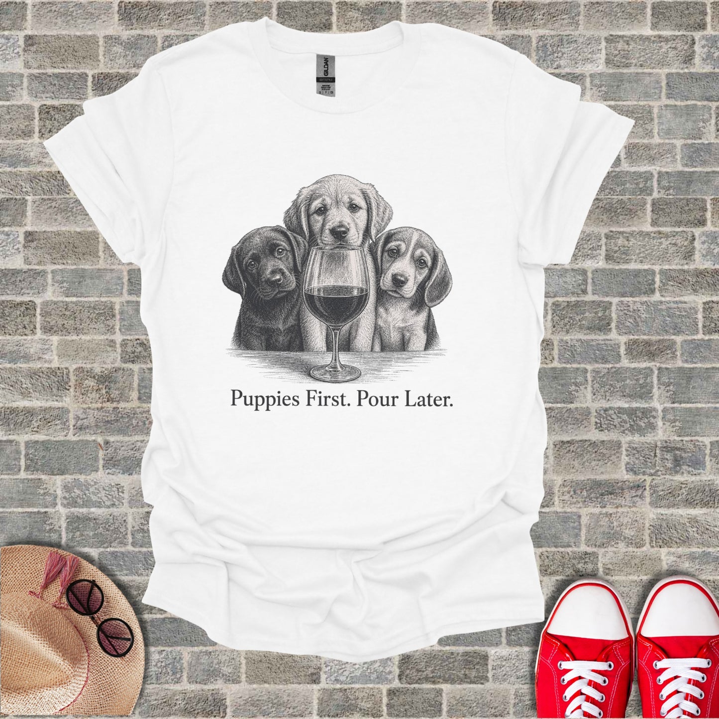 White t-shirt with three puppies and a wine glass, saying "Puppies First. Pour Later."