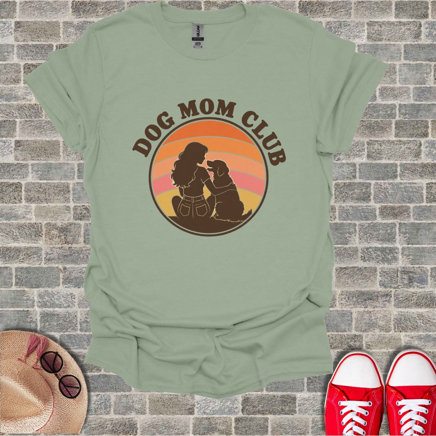 Green t-shirt with a circular graphic of a woman and dog under a sunset and "DOG MOM CLUB" text.