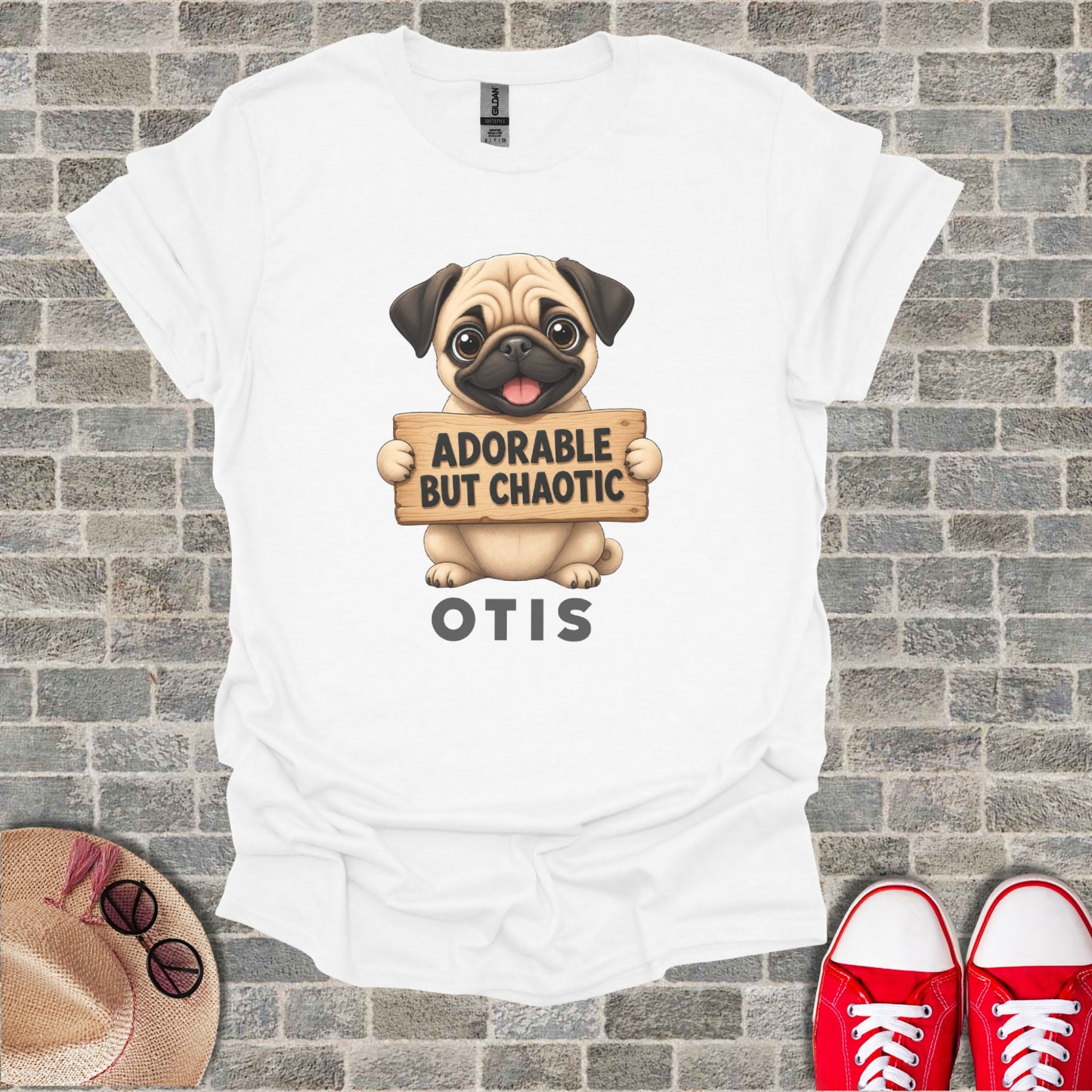 White t-shirt with a pug holding a sign that says "ADORABLE BUT CHAOTIC" and the name "OTIS".
