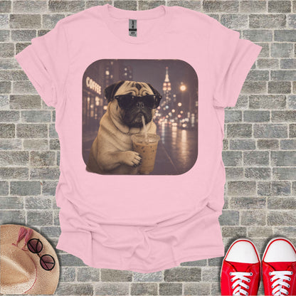 Pink t-shirt with a pug wearing sunglasses drinking iced coffee on a city street.