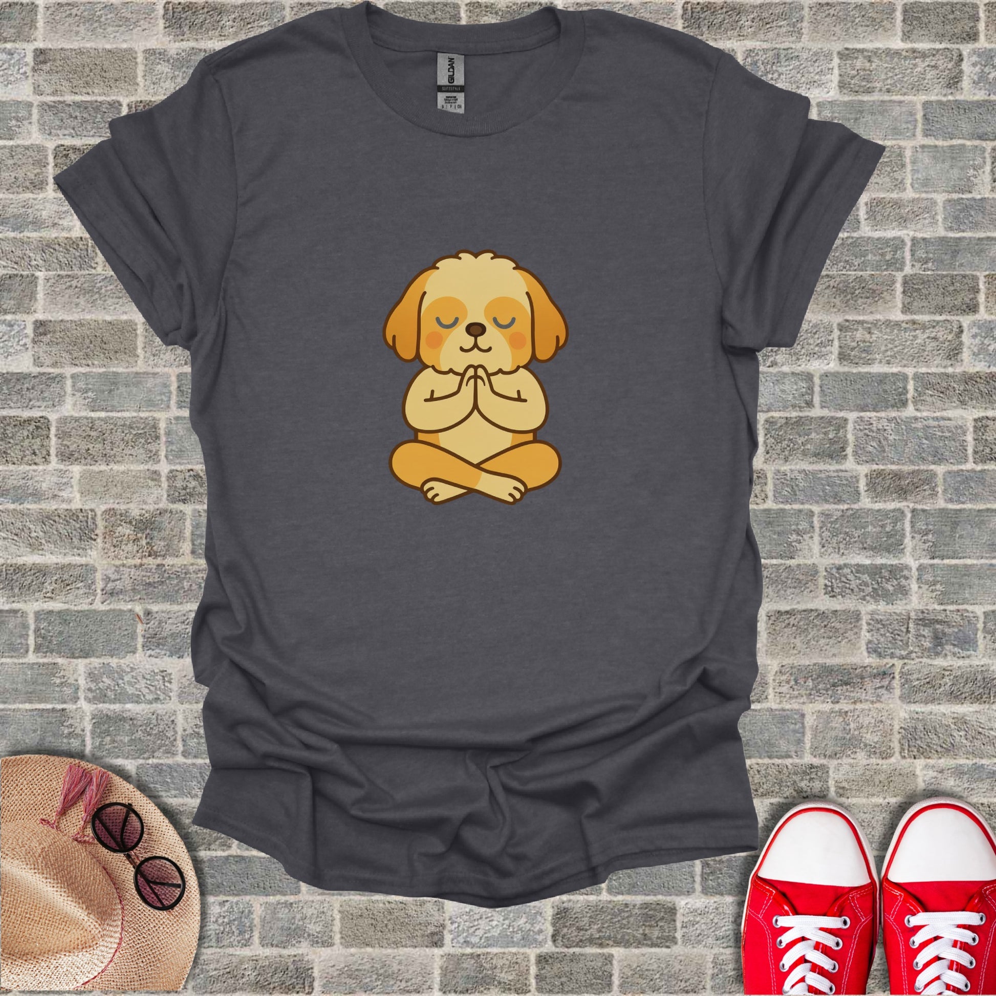 Dark grey t-shirt with a cartoon dog meditating on a brick background.